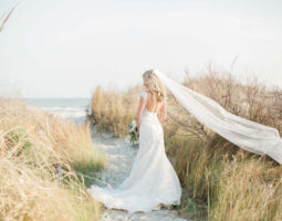 Bride standing on a beach with veil blowing